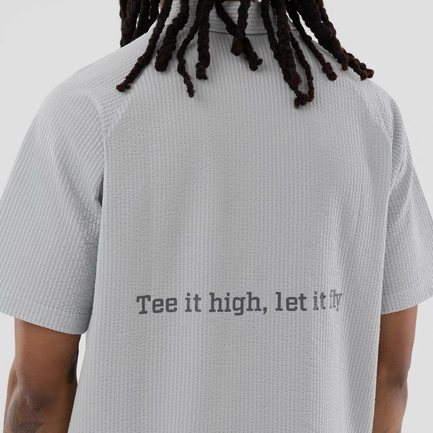 The model is wearing this New Era Seersucker Polo T-Shirt in grey. 6