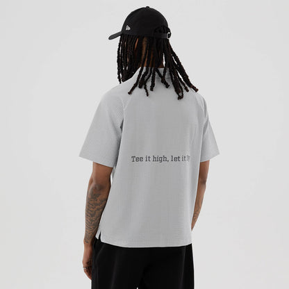 The model is wearing this New Era Seersucker Polo T-Shirt in grey. 2