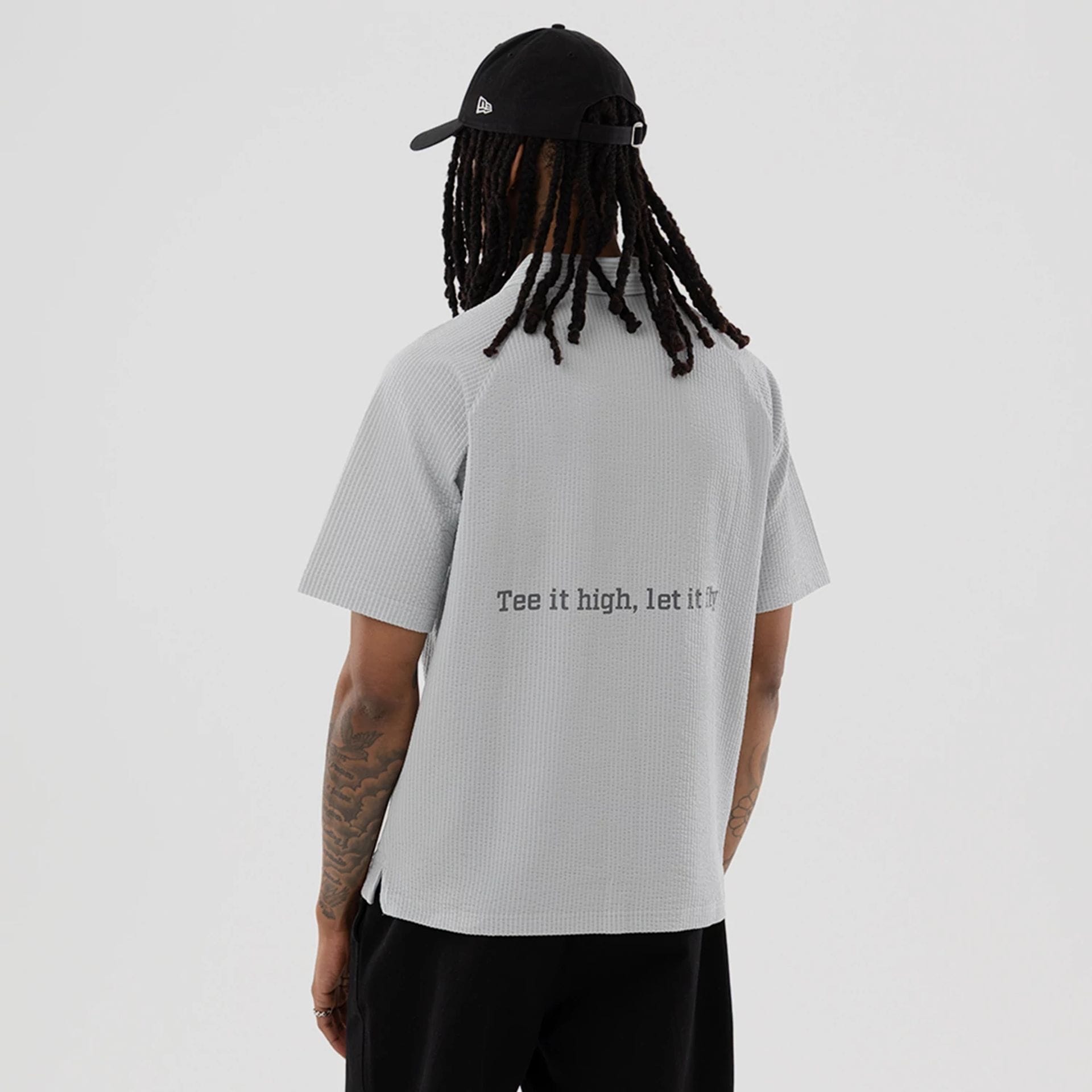 The model is wearing this New Era Seersucker Polo T-Shirt in grey. 2