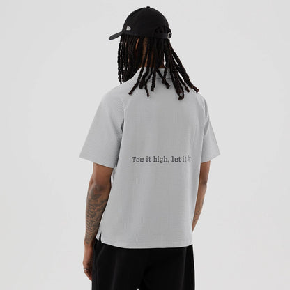 The model is wearing this New Era Seersucker Polo T-Shirt in grey. 2
