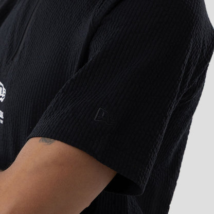 The model is wearing this New Era Seersucker Polo T-Shirt in black. 5