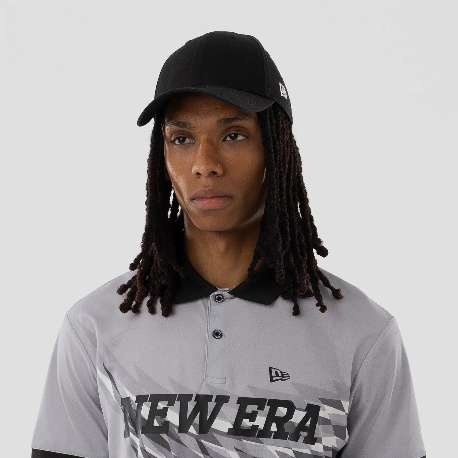 The model is wearing this New Era Grid Polo T-Shirt in grey. 4