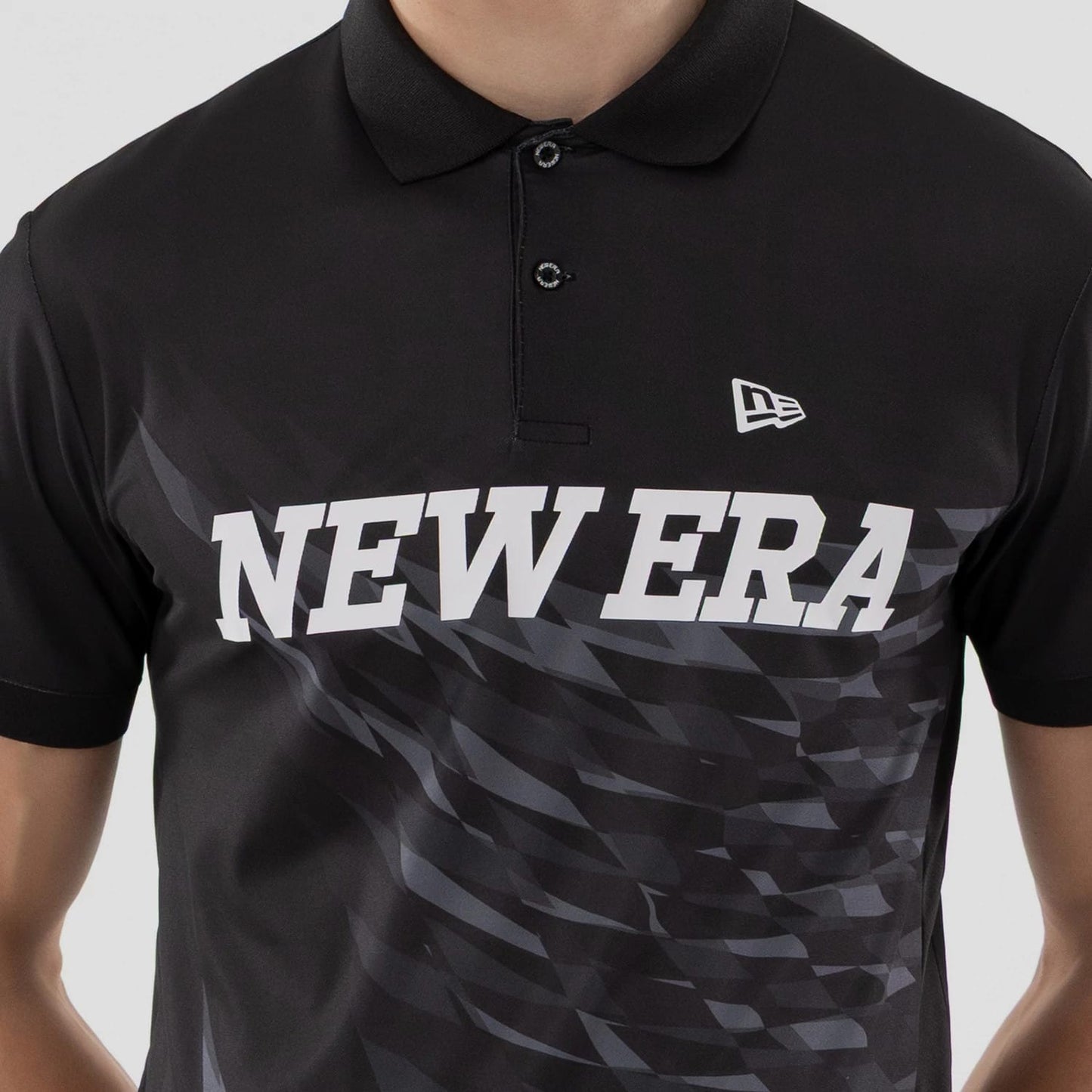 The model is wearing this New Era Grid Polo T-Shirt in black. 4