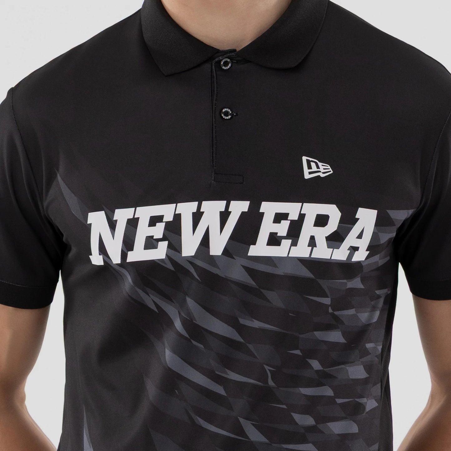 The model is wearing this New Era Grid Polo T-Shirt in black. 4