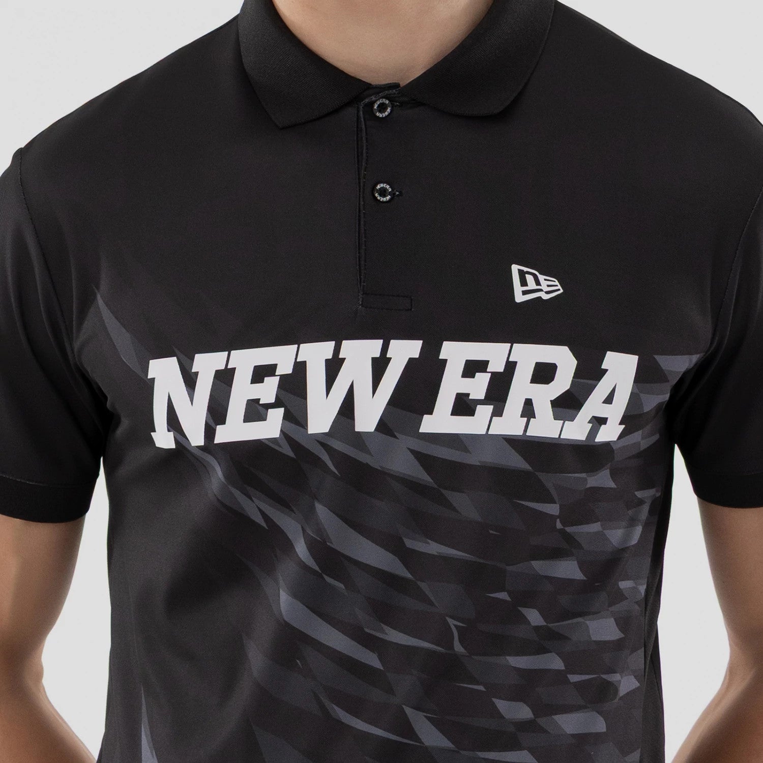 The model is wearing this New Era Grid Polo T-Shirt in black. 4