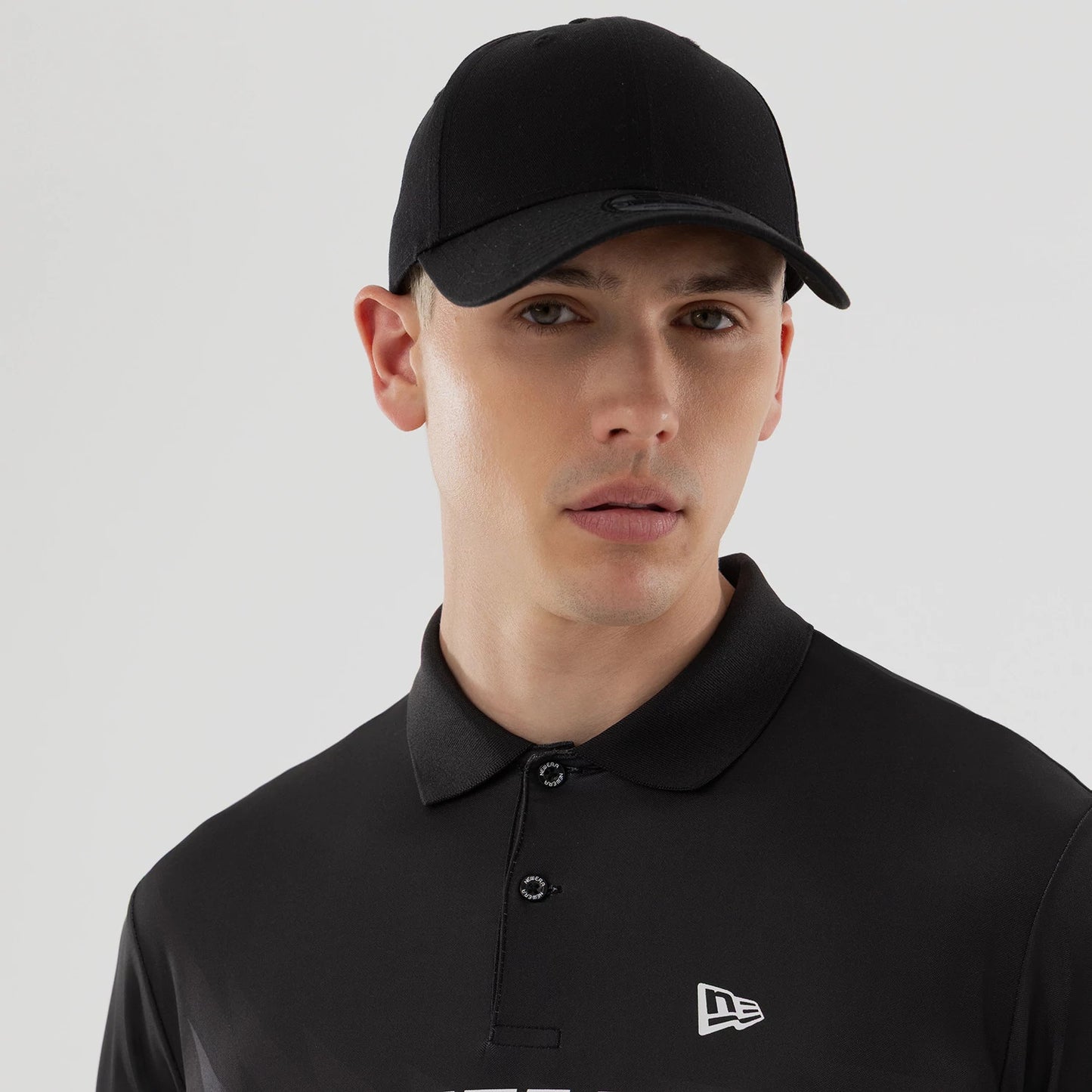 The model is wearing this New Era Grid Polo T-Shirt in black. 7