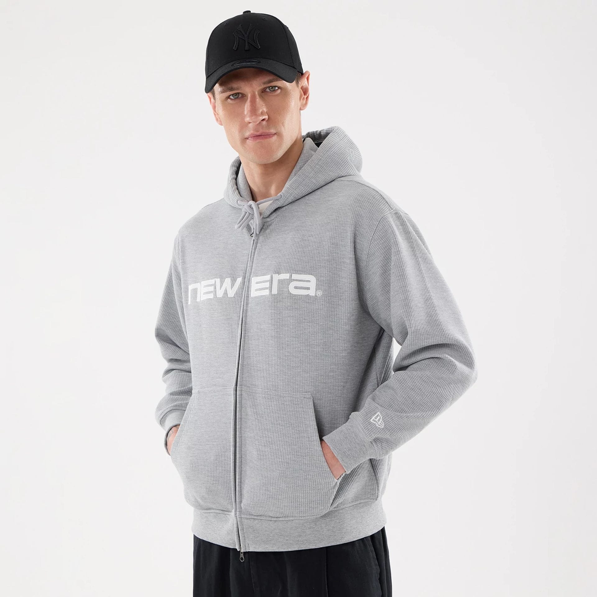 The model is wearing this New Era Waffle Full Zip Hoodie in grey. 1