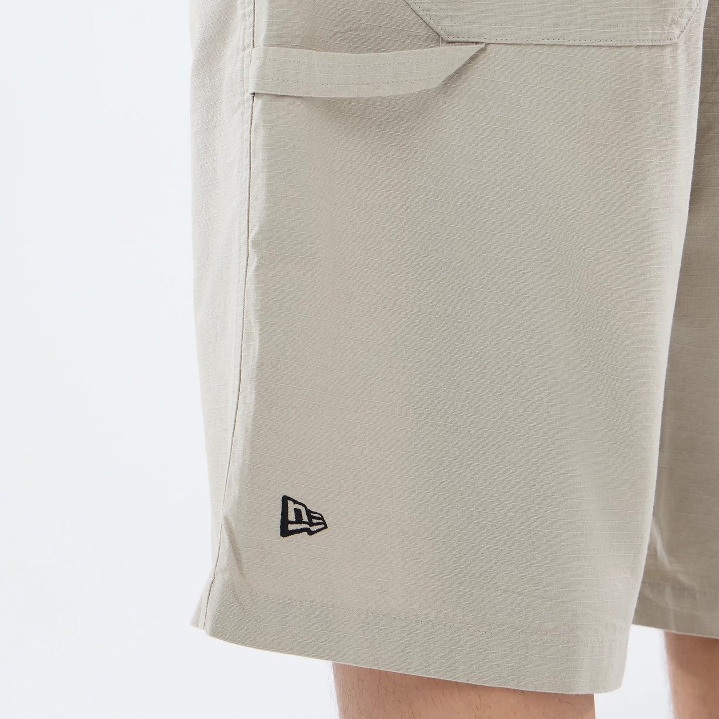 The model is wearing this New Era Canvas Bermuda Shorts in beige. 3