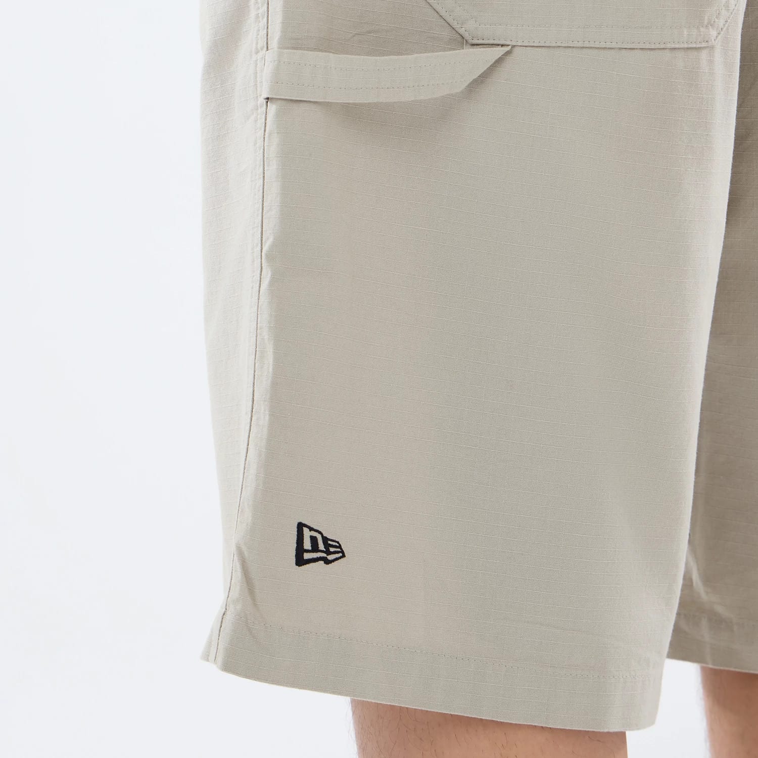 The model is wearing this New Era Canvas Bermuda Shorts in beige. 3