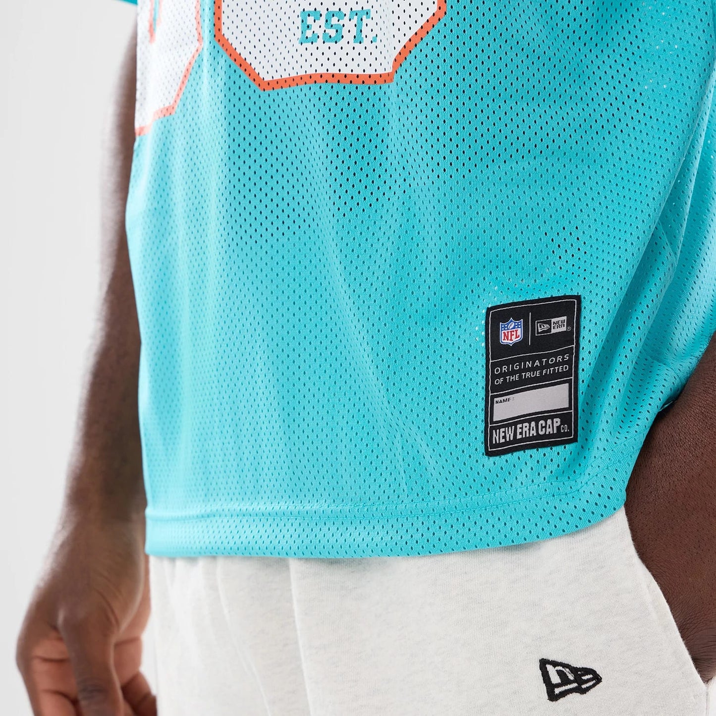 The model is wearing this NFL Miami Dolphins Mesh Jersey in turquoise. 4