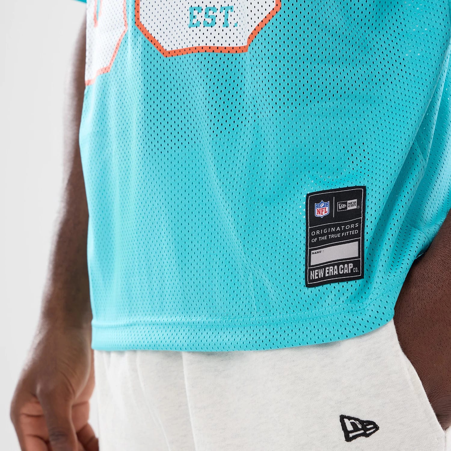The model is wearing this NFL Miami Dolphins Mesh Jersey in turquoise. 4