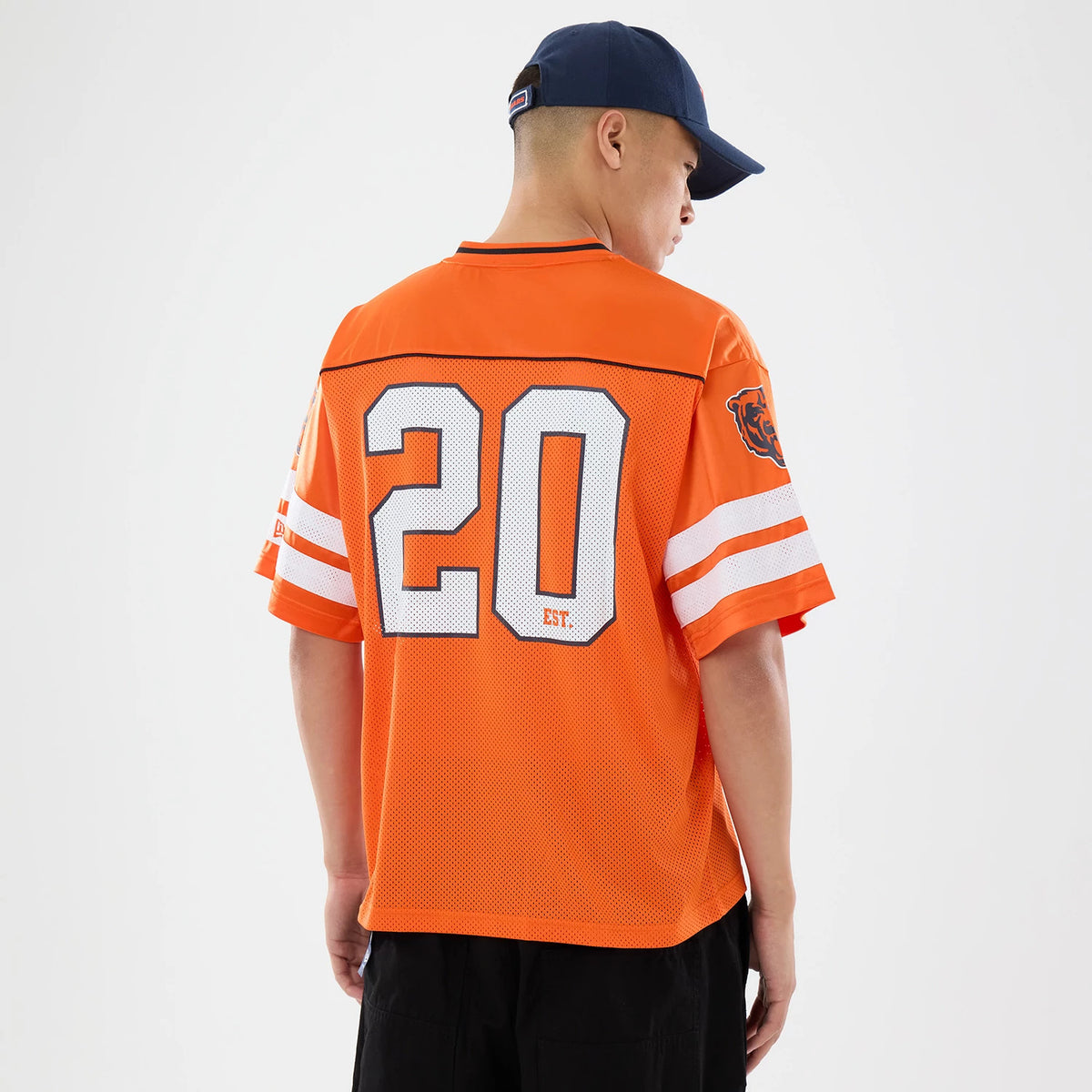 Chicago Bears NFL Orange Mesh Jersey, back view on a model wearing a blue cap, featuring large white number 20 with black outline, and a Bears logo patch on the left sleeve above double white stripes.