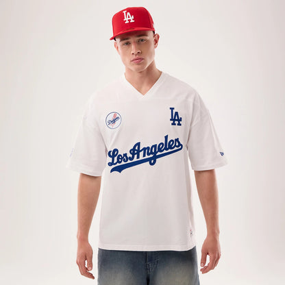 Los Angeles Dodgers MLB Fan Family White Jersey, front view on a model wearing a red cap, featuring a blue "Los Angeles" script across the chest, LA logo on the right side and a Dodgers patch on the left chest.