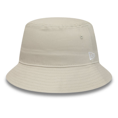 New Era Essential Tapered Stone Bucket Hat, side view showing the white embroidered New Era flag logo on the left side, with a soft rounded crown and a wide downsloping brim in stone colour.