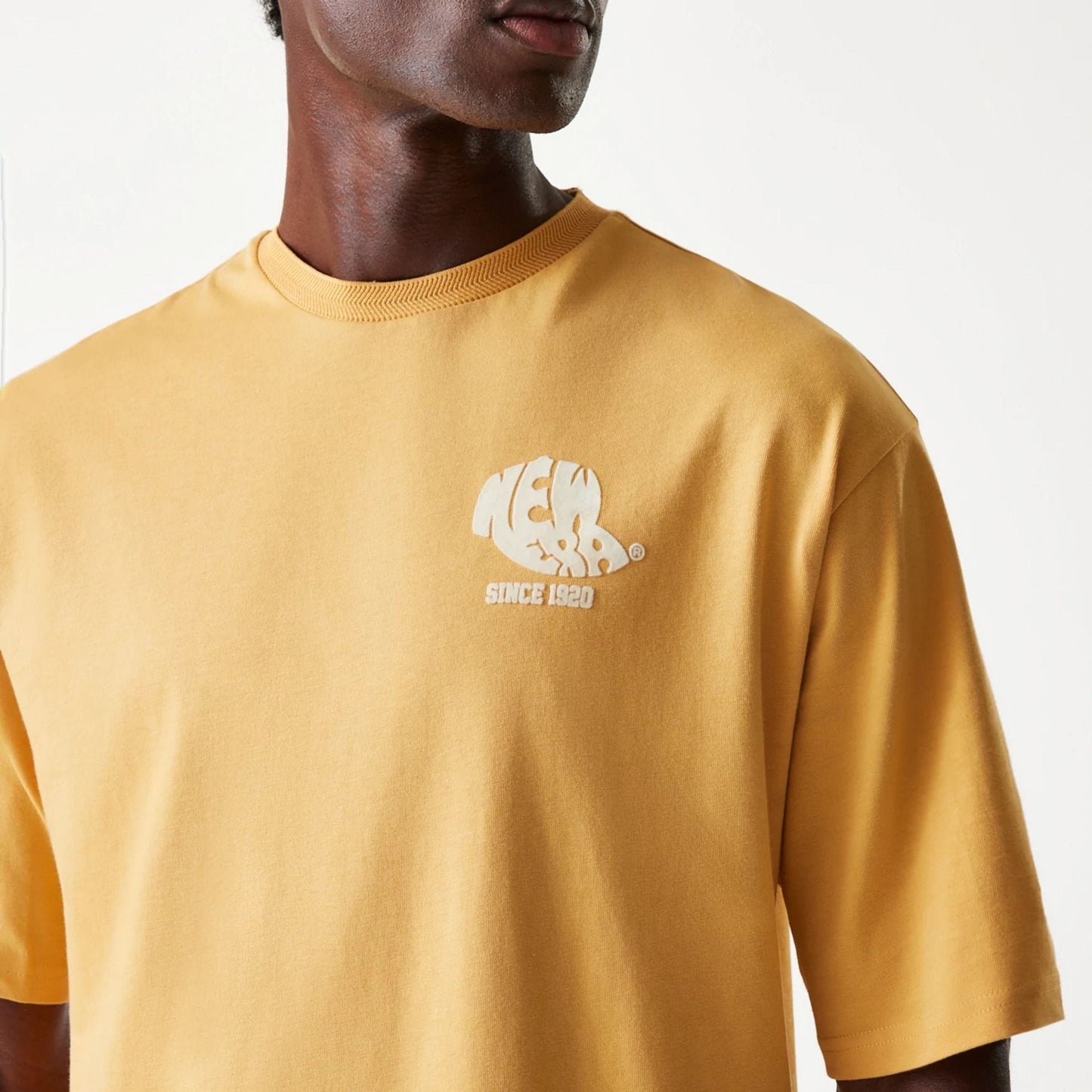 The Male model is wearing New Era Graphic Beige Oversized T-Shirt 5