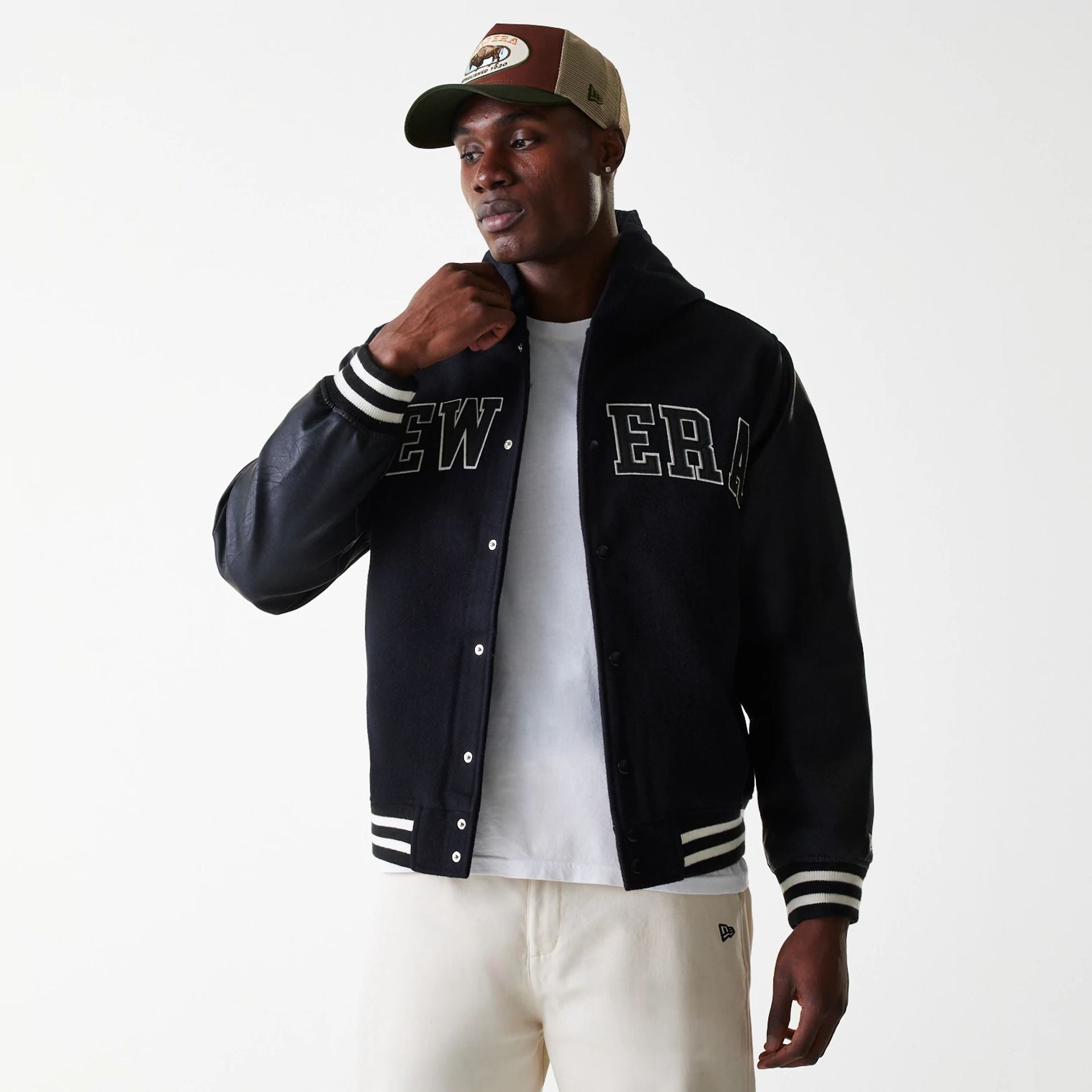 The Male model is wearing New Era Black Hooded Varsity Jacket 3