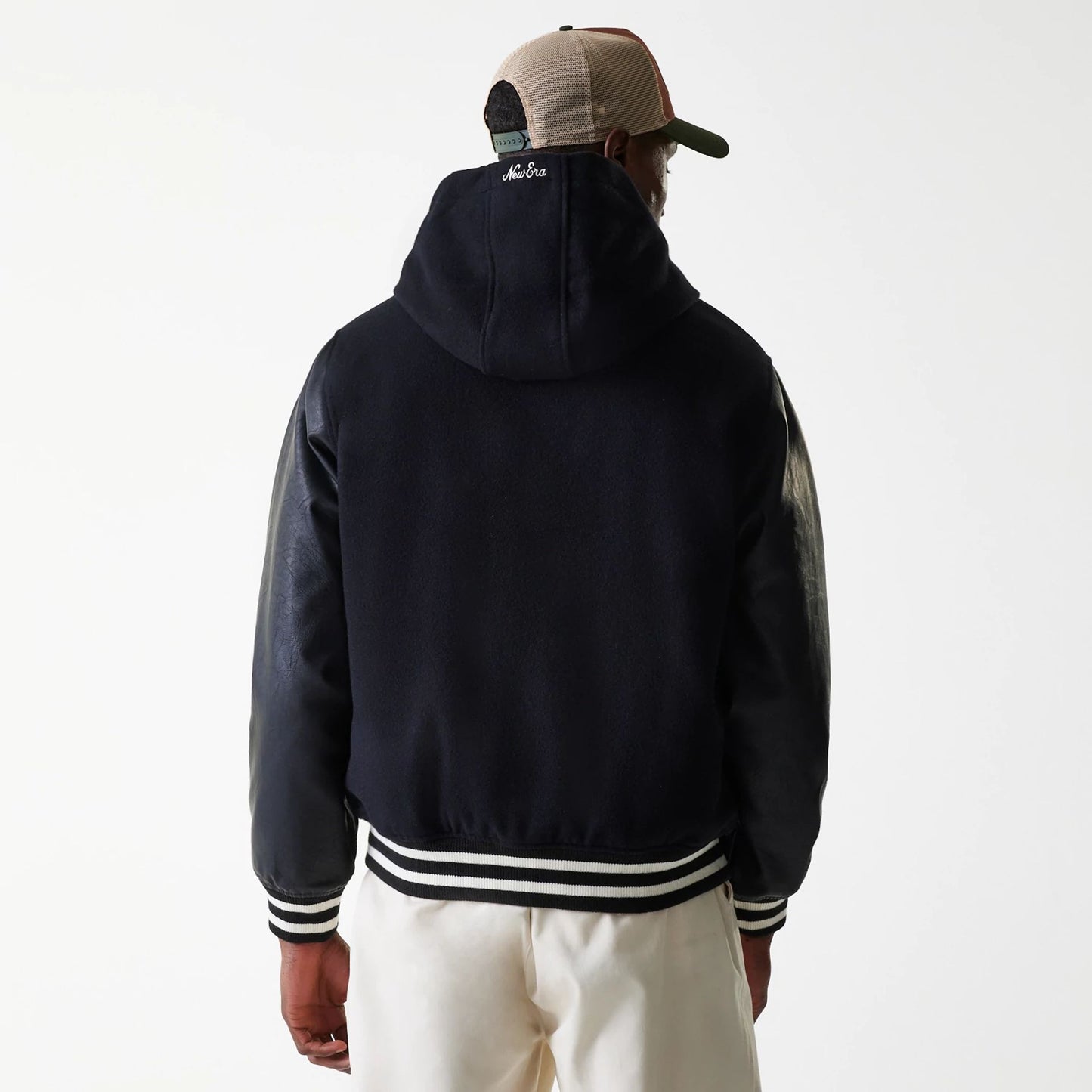 The Male model is wearing New Era Black Hooded Varsity Jacket 2