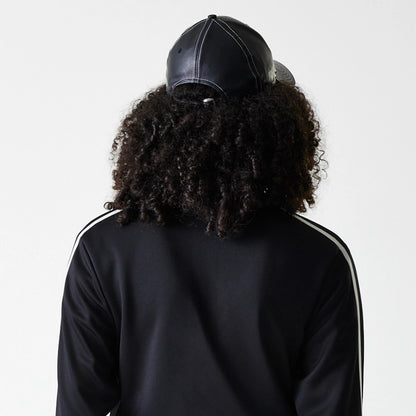 New Era New York Yankees Womens MLB Midi Logo Black Track Jacket, rear view showing the black fabric with white stripes along the sleeves and a person wearing a black cap with eyelets seen from behind.