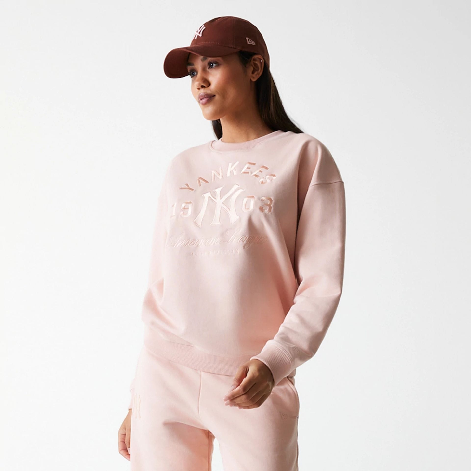 The Female model is wearing New York Yankees Womens MLB Tonal Graphic Pastel Pink Oversized Crew Neck Sweater 3