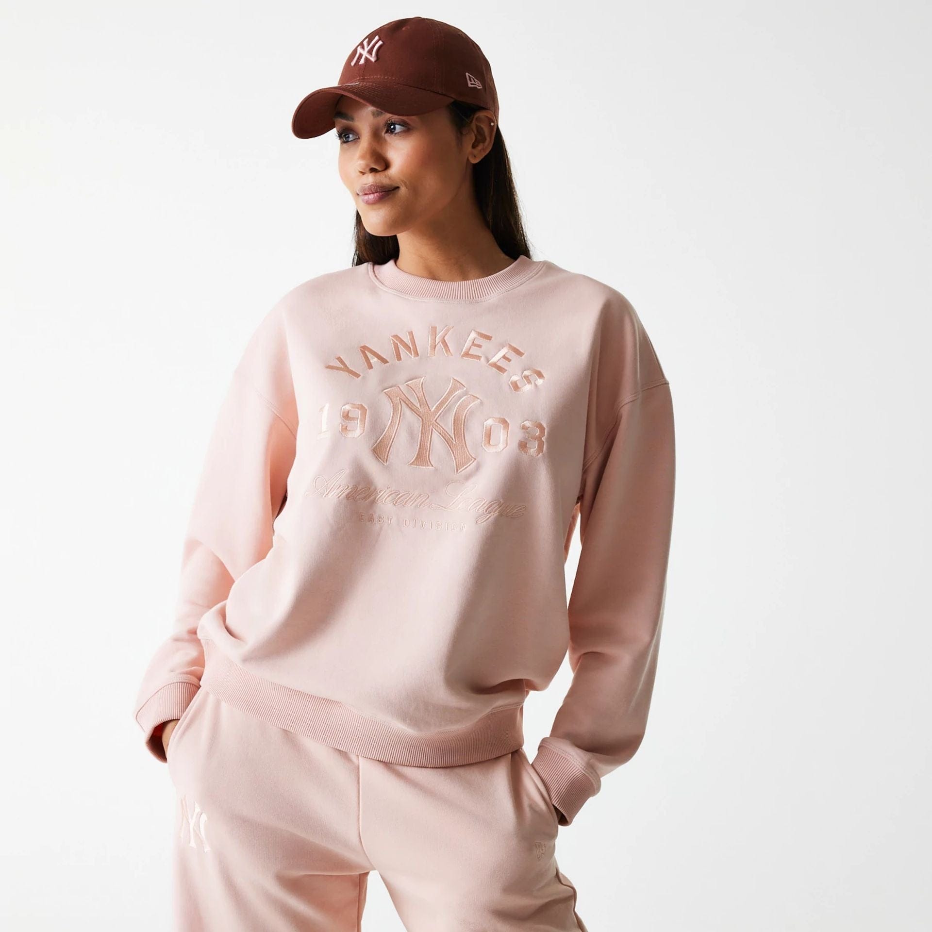 The Female model is wearing New York Yankees Womens MLB Tonal Graphic Pastel Pink Oversized Crew Neck Sweater 1