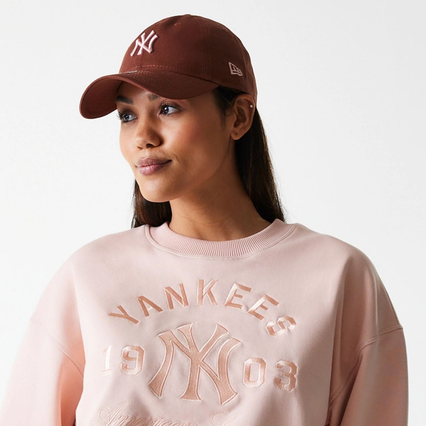 The Female model is wearing New York Yankees Womens MLB Tonal Graphic Pastel Pink Oversized Crew Neck Sweater 6