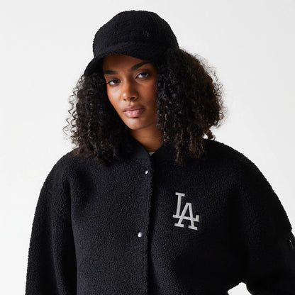 New Era LA Dodgers Womens MLB Black Oversized Sherpa Bomber Jacket, on-model view showing a large white embroidered LA logo on the left chest and a black cap with a small black embossed LA logo on the front.