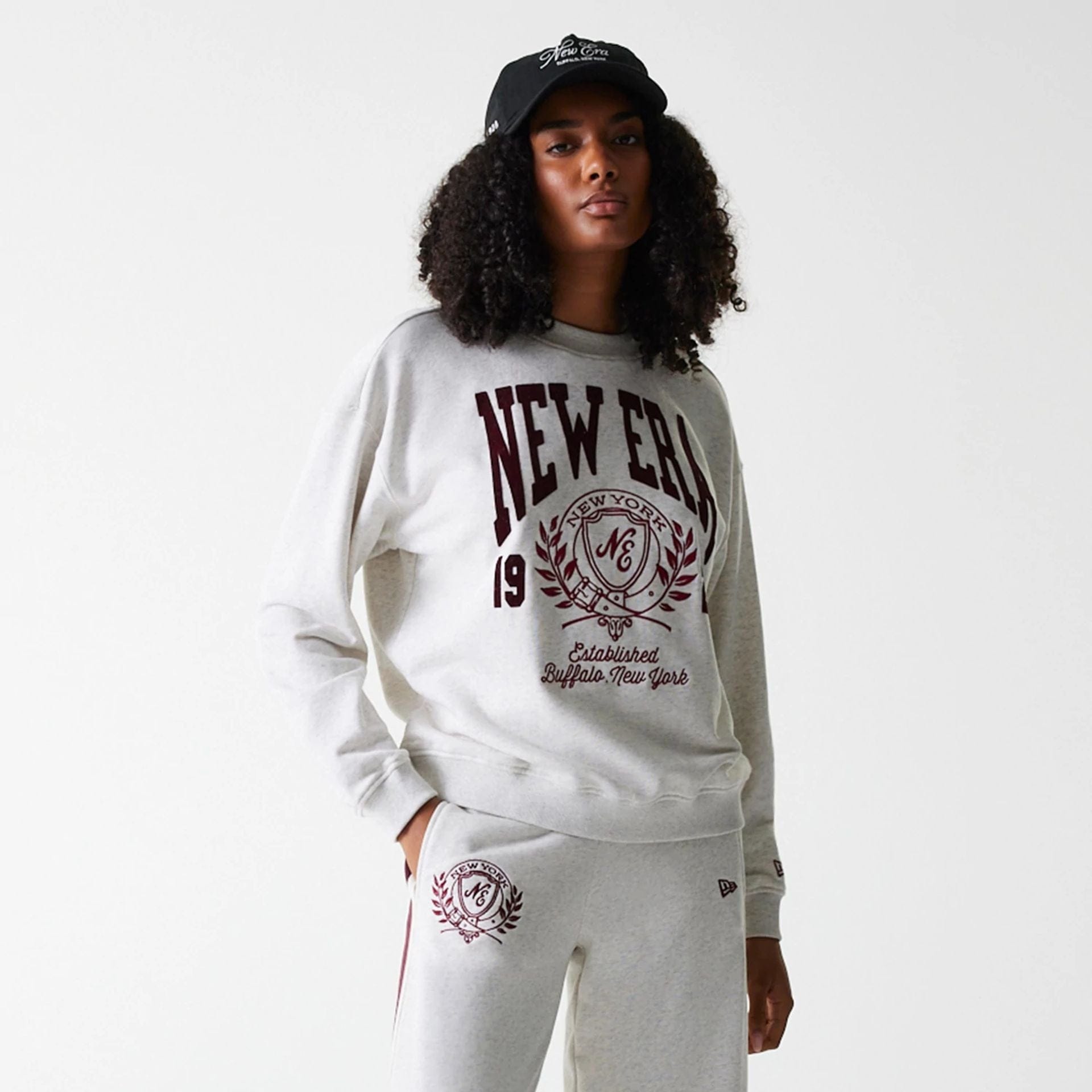 The Female model is wearing Womens New Era Crest Graphic Pastel Grey Crew Neck Sweater 4