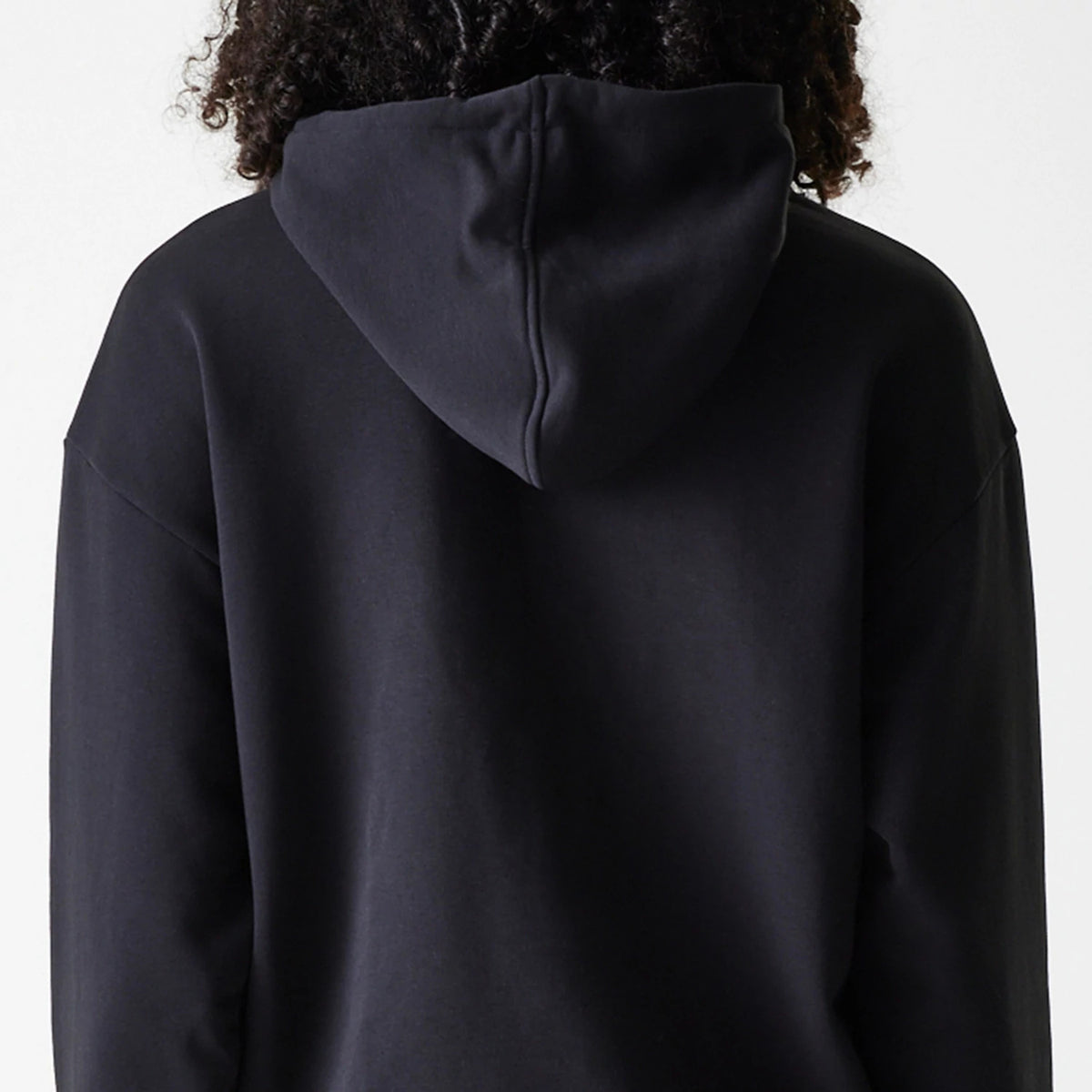 Womens New Era Crest Black Pullover Hoodie, rear view showing the plain black hood positioned centrally on the back, attached to the long black sleeves, and the simple seam detail running down the middle of the hood.