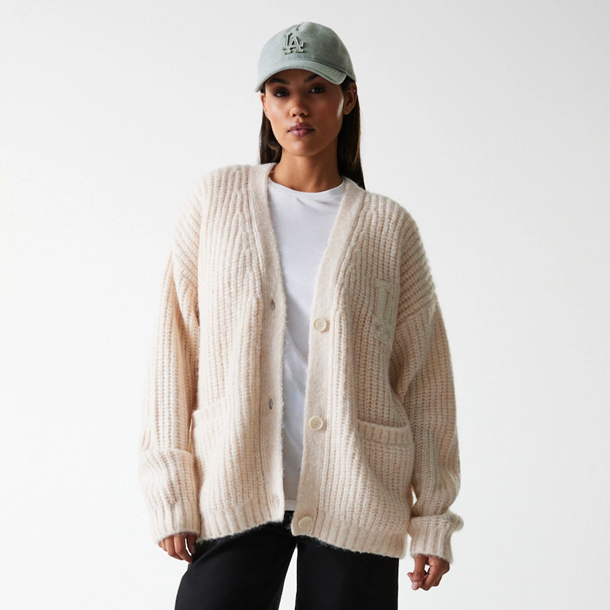 New Era LA Dodgers Womens MLB Knit Light Beige Cardigan, front view on a model with a light blue cap, showing ribbed texture, embroidered LA logo on the upper chest, and large front pockets.