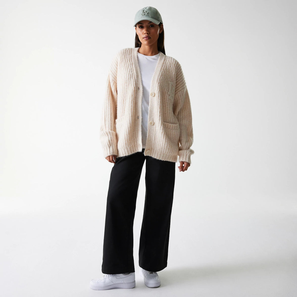 New Era LA Dodgers Womens MLB Knit Light Beige Cardigan, front view on a model wearing a white t-shirt, black trousers, and white trainers, with a light grey cap featuring a raised embroidered LA Dodgers logo on the front panel.