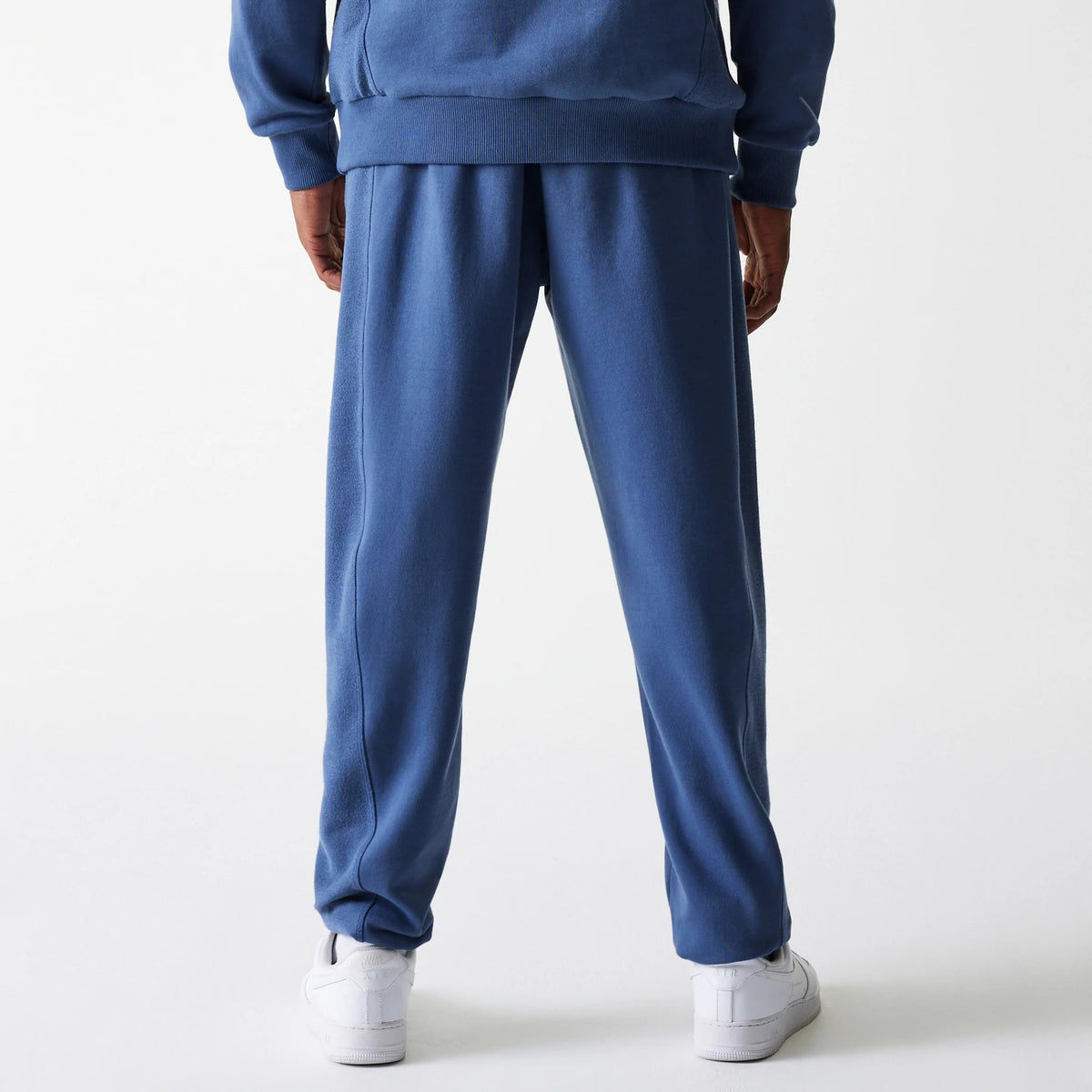 New Era LA Lakers NBA Arch Graphic Dark Blue Joggers, rear view on a model wearing a matching dark blue sweatshirt, showcasing the straight leg fit and elasticated waistband above white trainers.