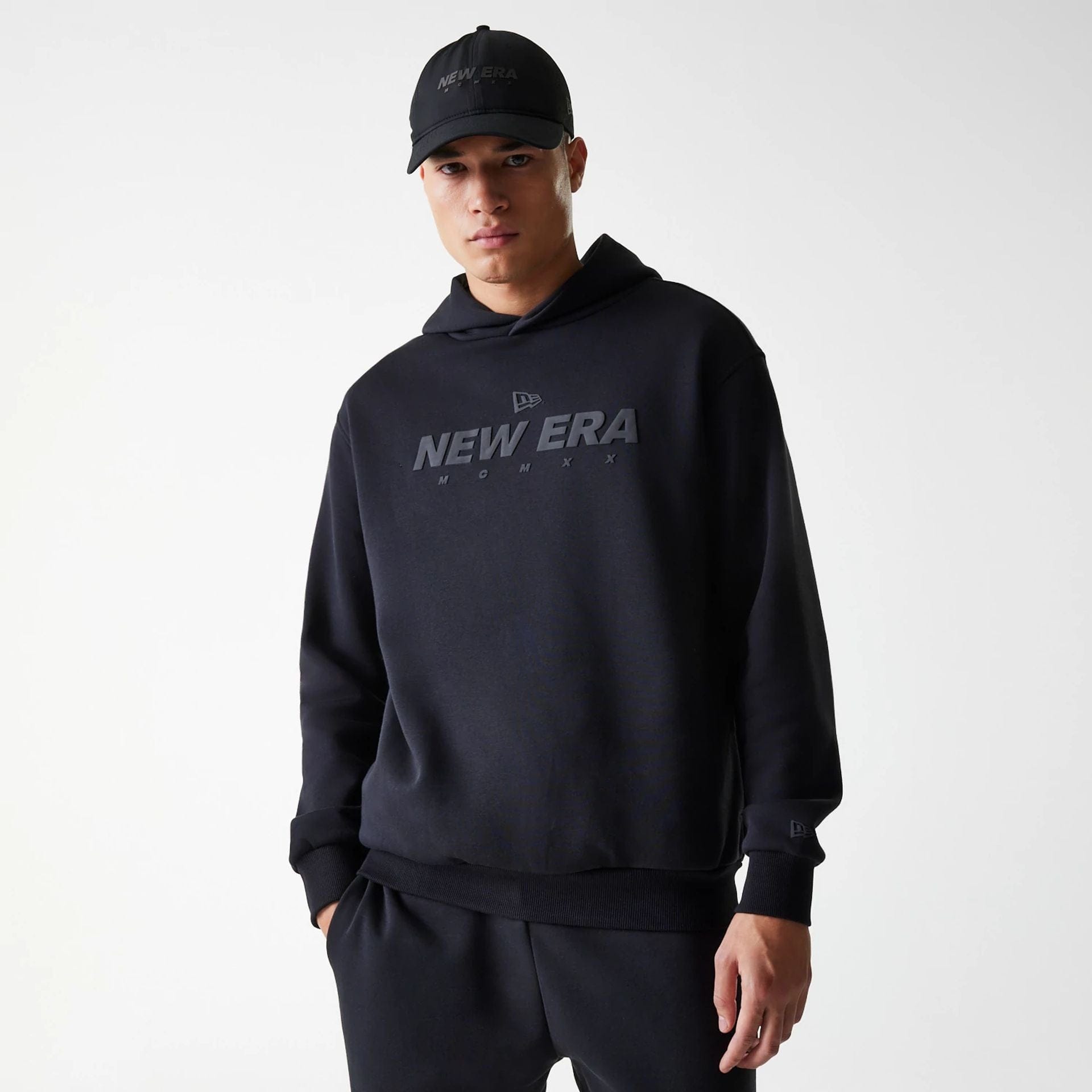 The Male model is wearing New Era Tech Black Oversized Pullover Hoodie 1