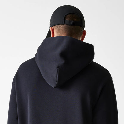 New Era Tech Black on Black Oversized Pullover Hoodie, rear view showing the oversized hood draping over shoulders, with a black debossed New Era logo on a black cap worn by the model.
