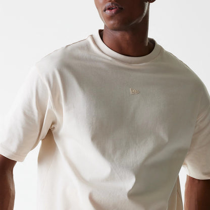 New Era Tech Light Beige Oversized T-Shirt, front view showing a debossed logo positioned on the upper left chest of the light beige oversized design, with a crew neck and short sleeves.