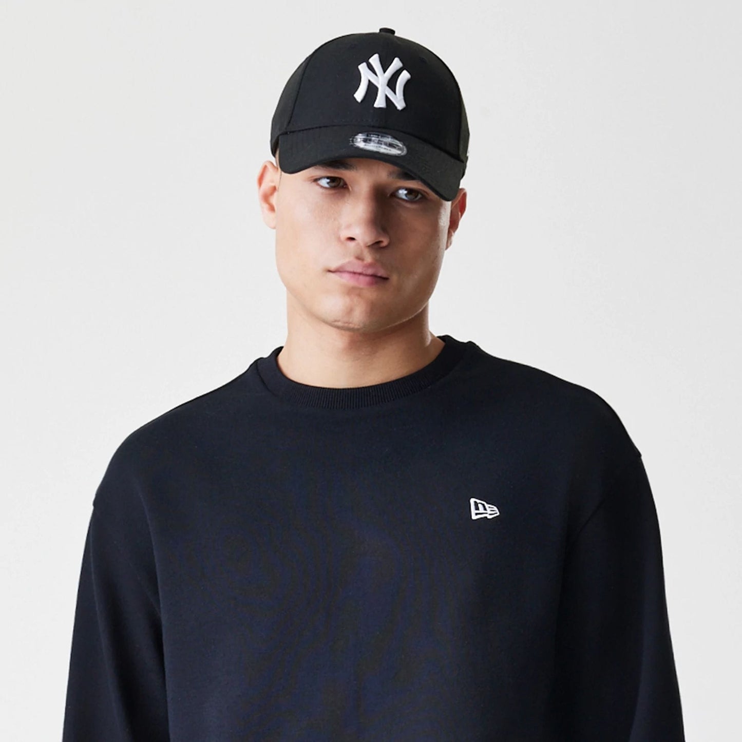 The Male model is wearing New Era Premium Essential Black Oversized Crew Neck Sweater 6