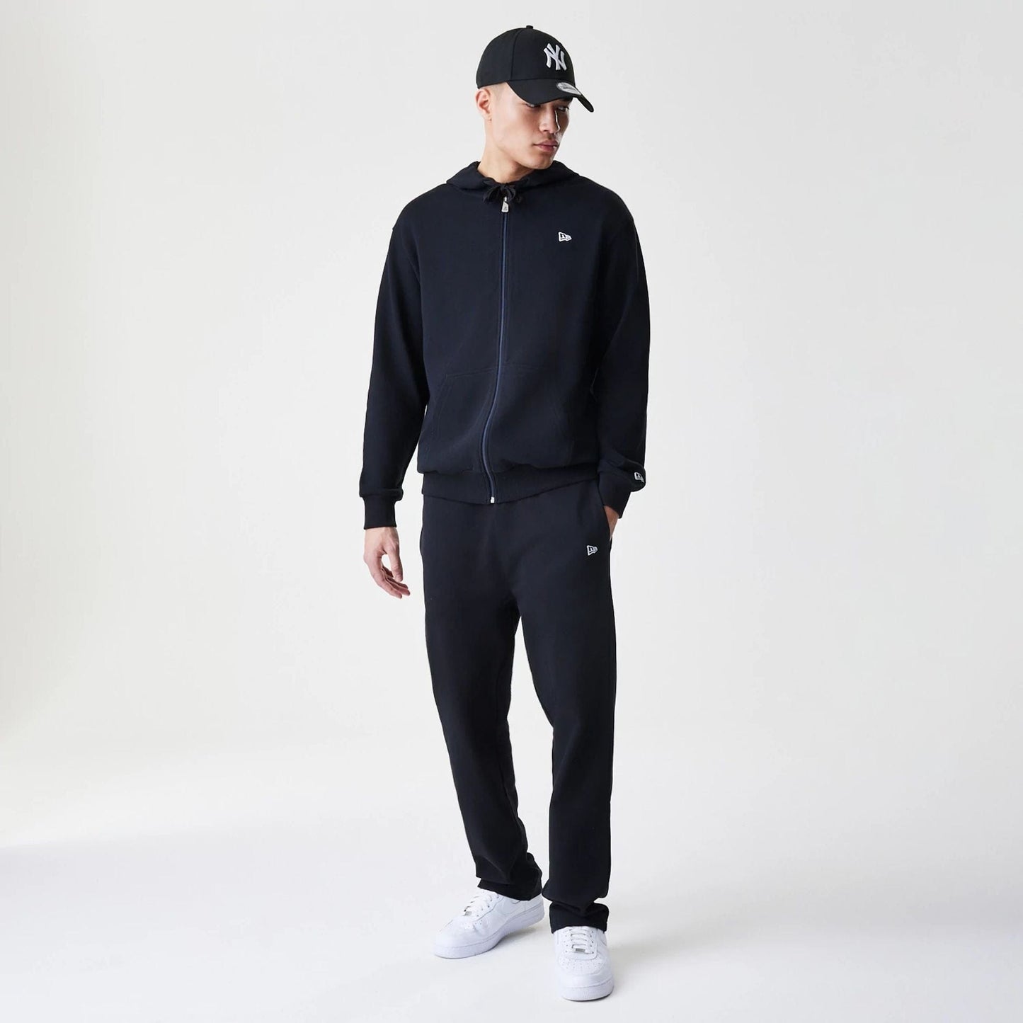 The Male model is wearing New Era Premium Essential Black Oversized Full Zip Hoodie 8