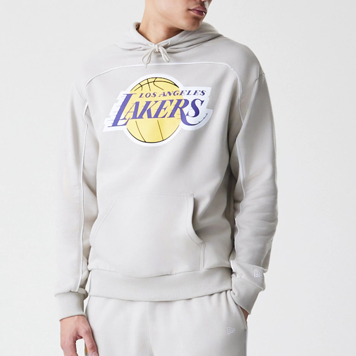 New Era LA Lakers NBA Piping Cream Oversized Pullover Hoodie, front view on a model showing the large printed Lakers logo on the chest, a kangaroo pocket, and ribbed cuffs, with a New Era embroidered logo on the left sleeve.