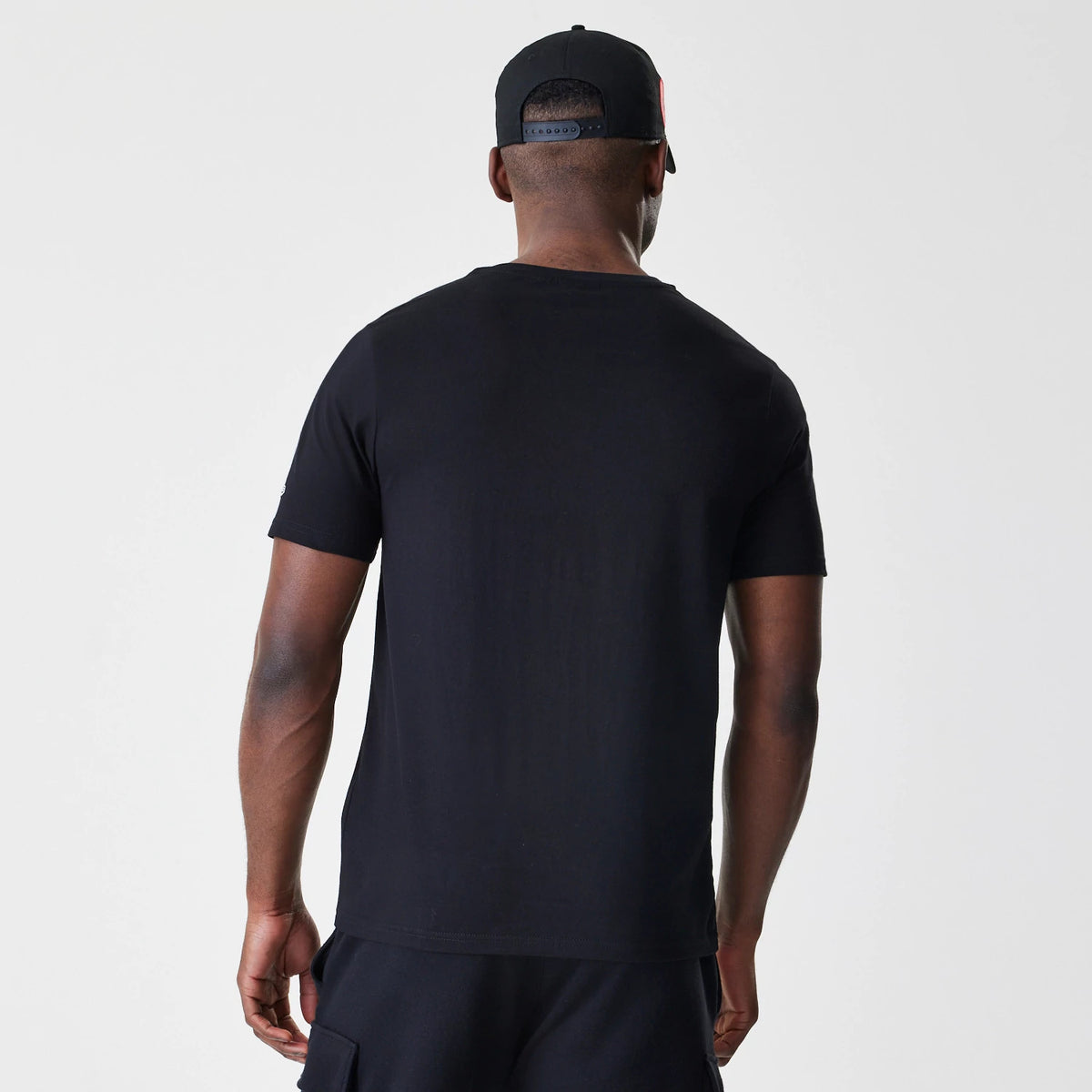 New Era Chicago Bulls NBA Script Black T-Shirt, back view on a model with a cap, showing a plain black back with short sleeves and a crew neckline, no graphics or logos.