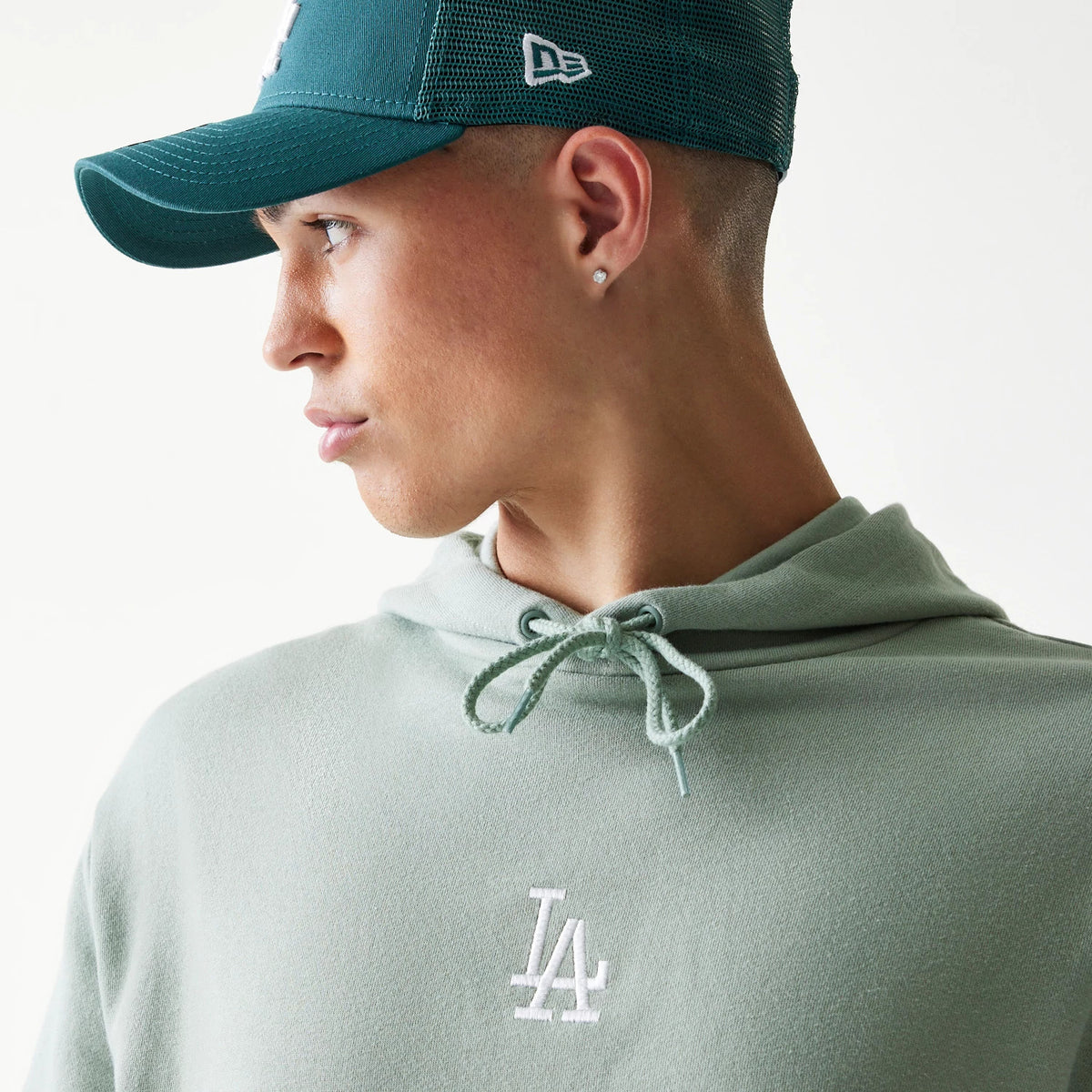 New Era LA Dodgers MLB Midi Pastel Green Oversized Pullover Hoodie, front view on-model showing the embroidered white LA logo on the chest and a drawstring at the neck, styled with a matching cap.