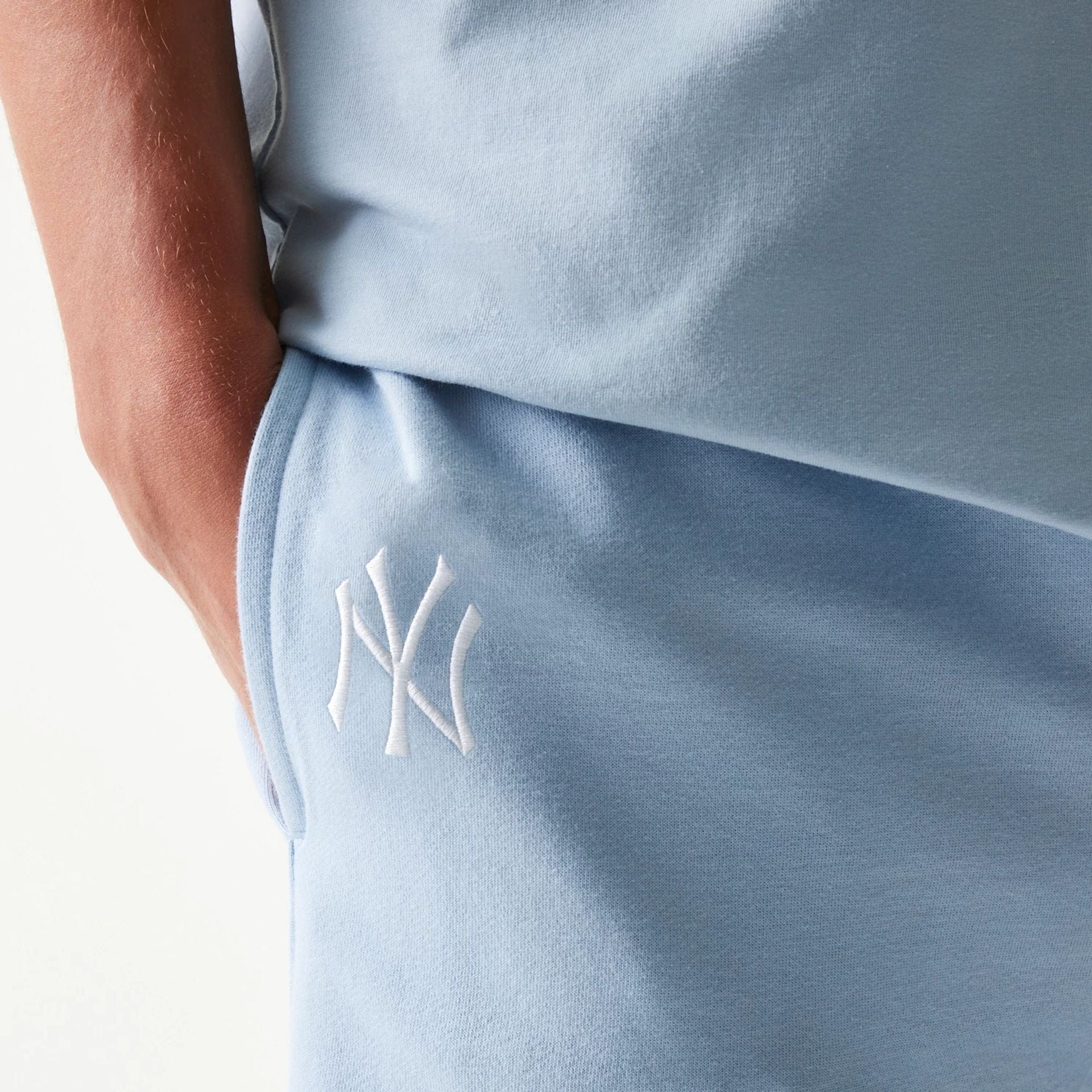 The model is wearing this MLB League Essential Midi New York Yankees Shorts in pastel blue. 4