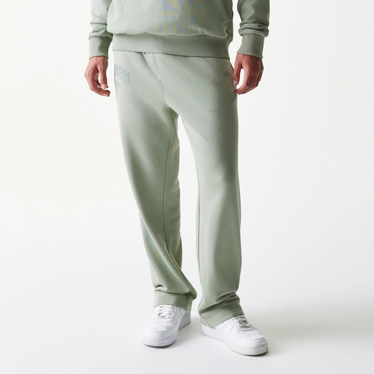 New Era LA Lakers NBA Pastel Green Straight Leg Joggers, front view on a model wearing matching top and white trainers, showing the embroidered Lakers logo on the left thigh and ribbed cuffs at the ankle.