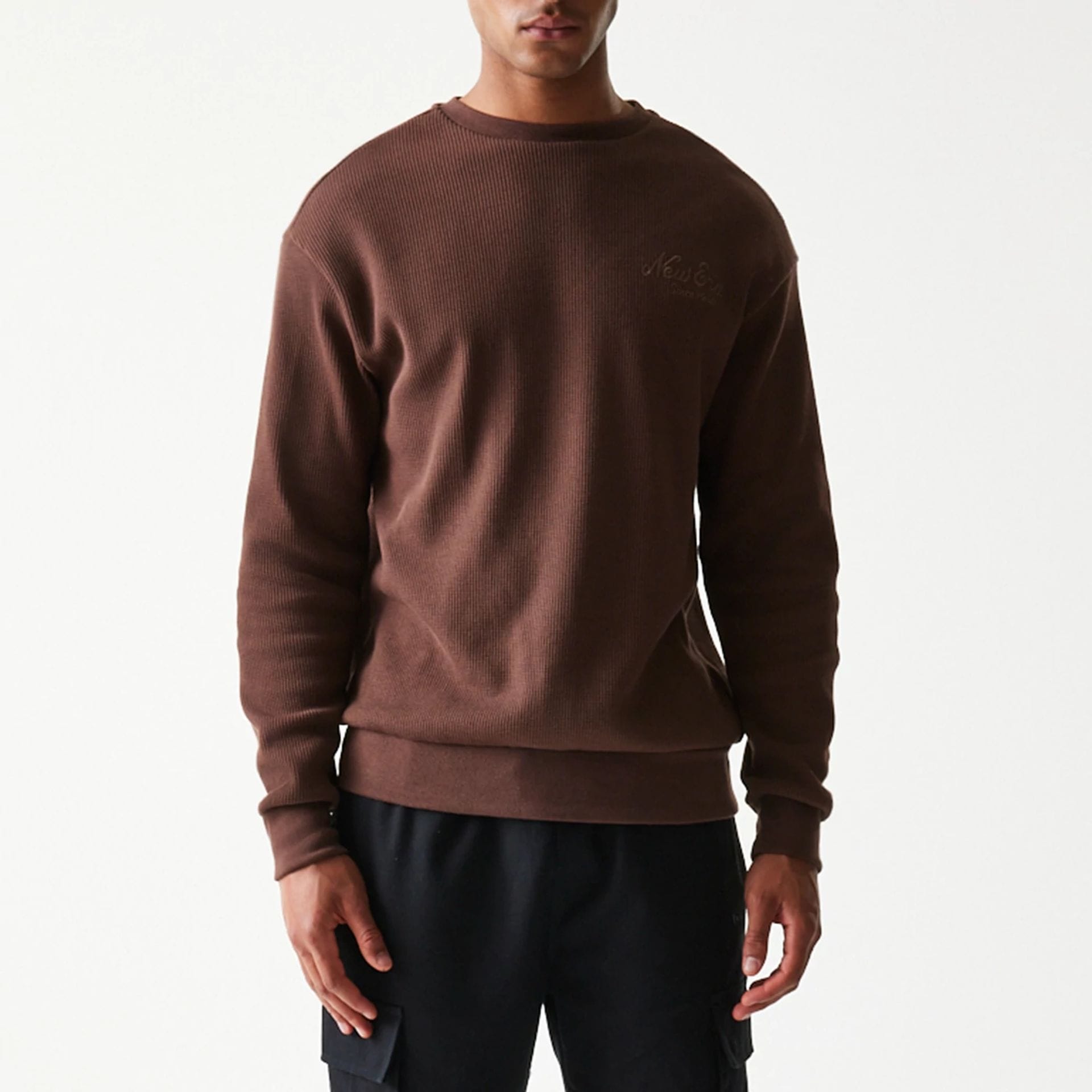 The model is wearing this New Era Script Waffle Crew Neck Sweater in brown. 5