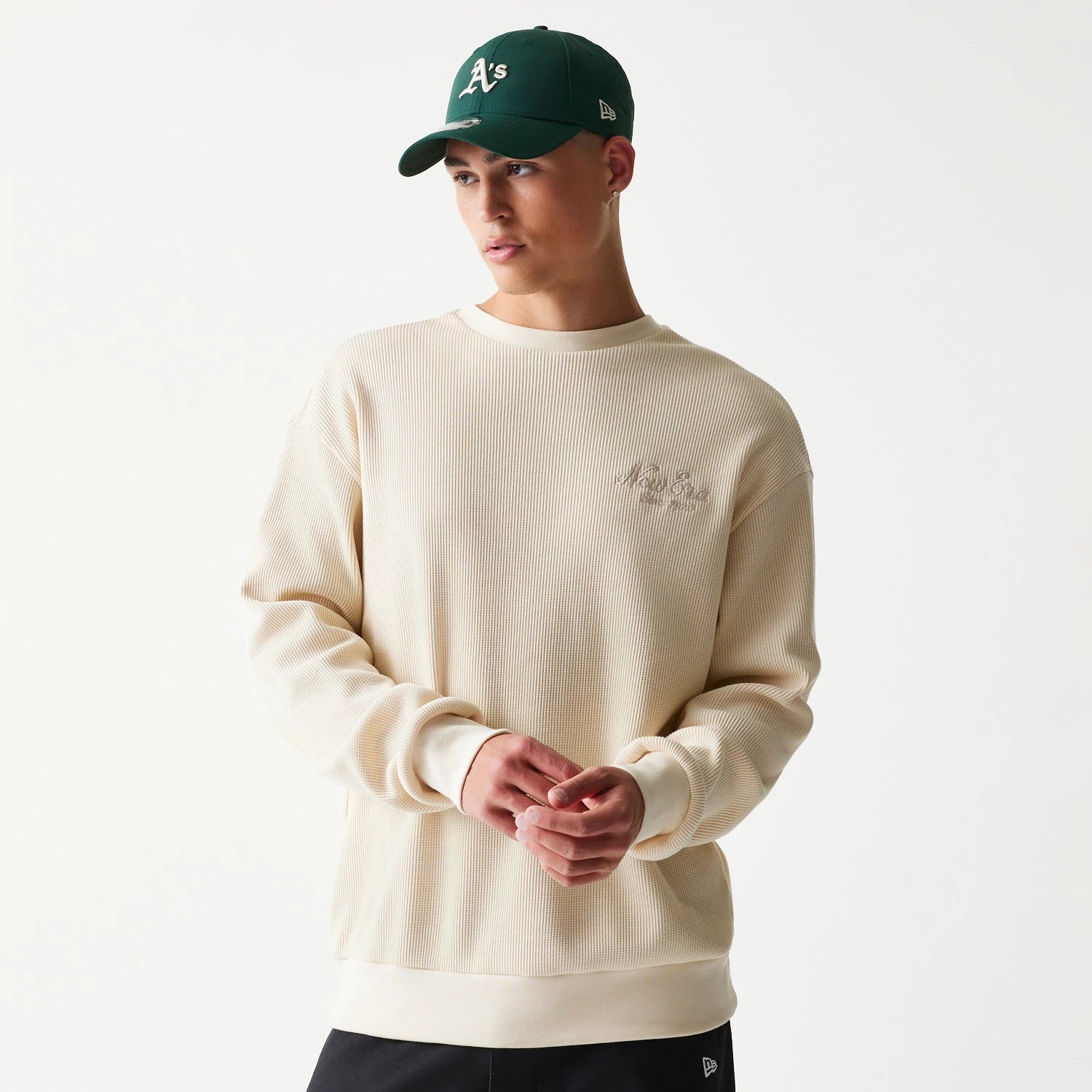 The model is wearing this New Era Script Waffle Crew Neck Sweater in light beige. 3