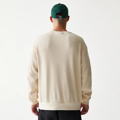 The model is wearing this New Era Script Waffle Crew Neck Sweater in light beige. 2