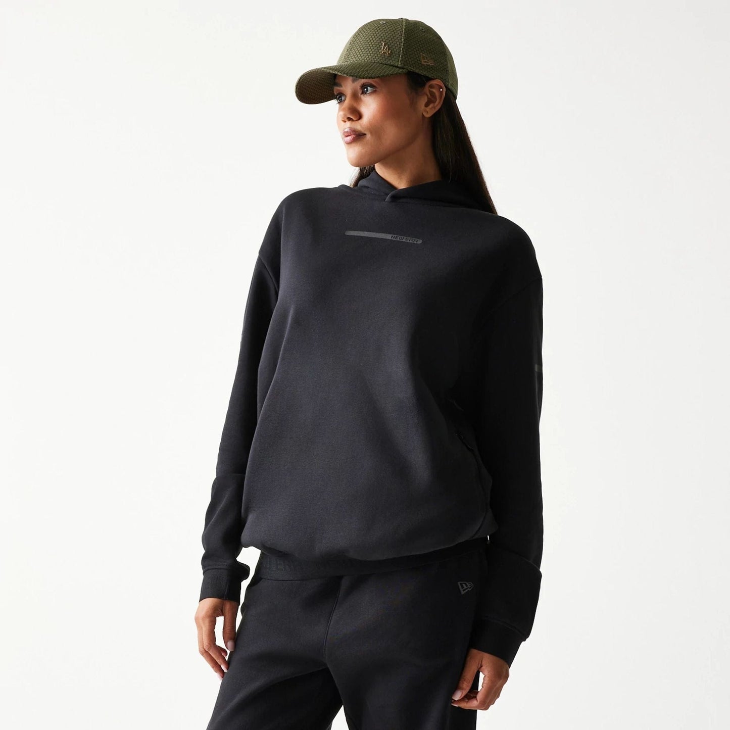 The model is wearing this New Era Tech Oversized Pullover Hoodie in black. 4
