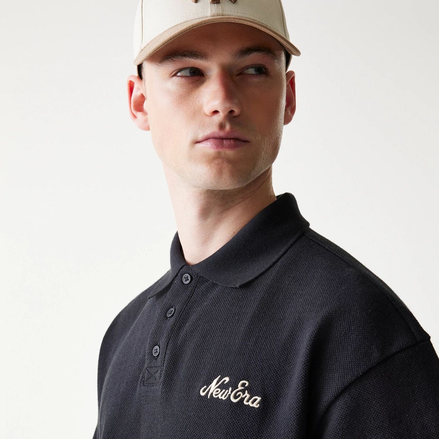 The model is wearing this New Era Graphic Polo T-Shirt in black. 4