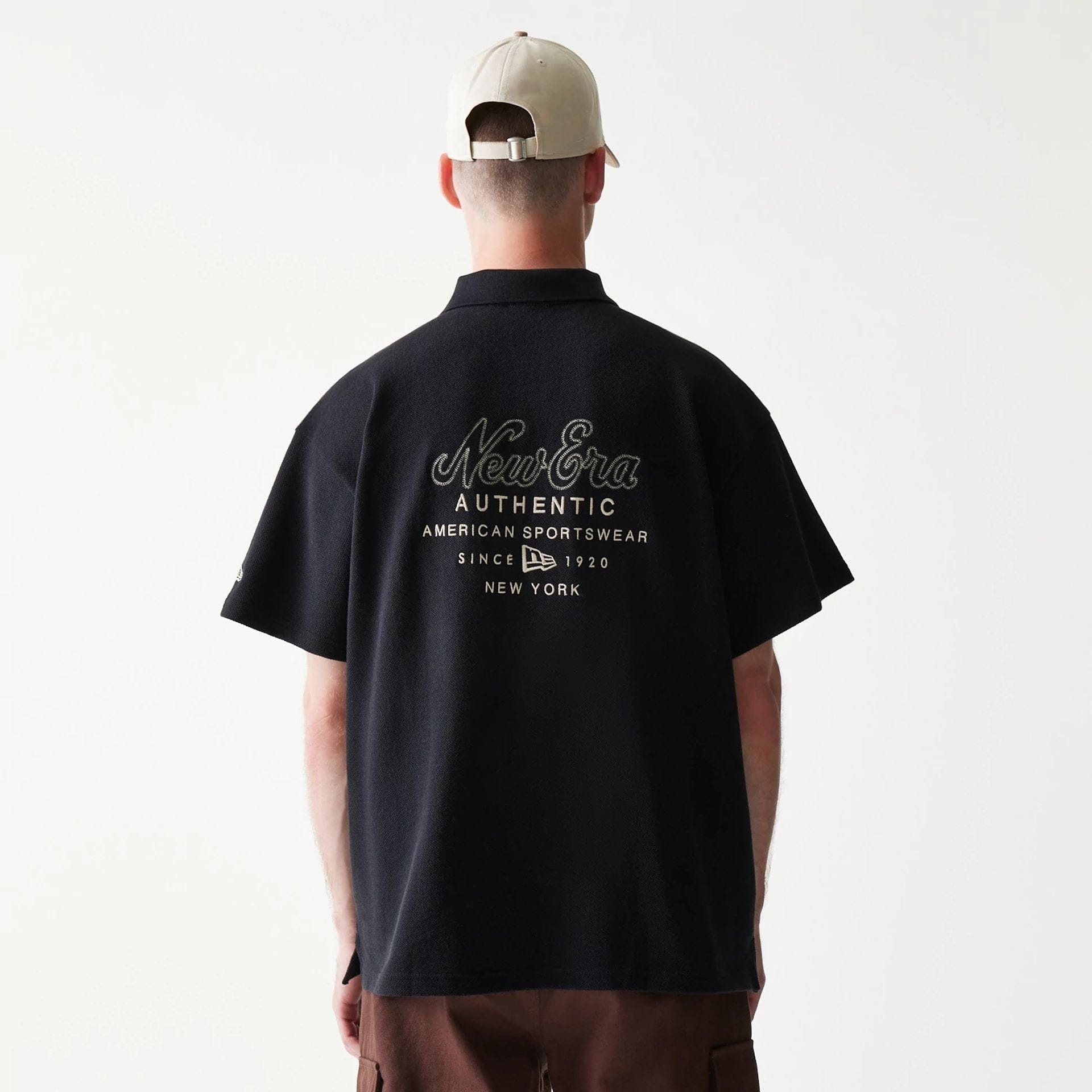The model is wearing this New Era Graphic Polo T-Shirt in black. 2