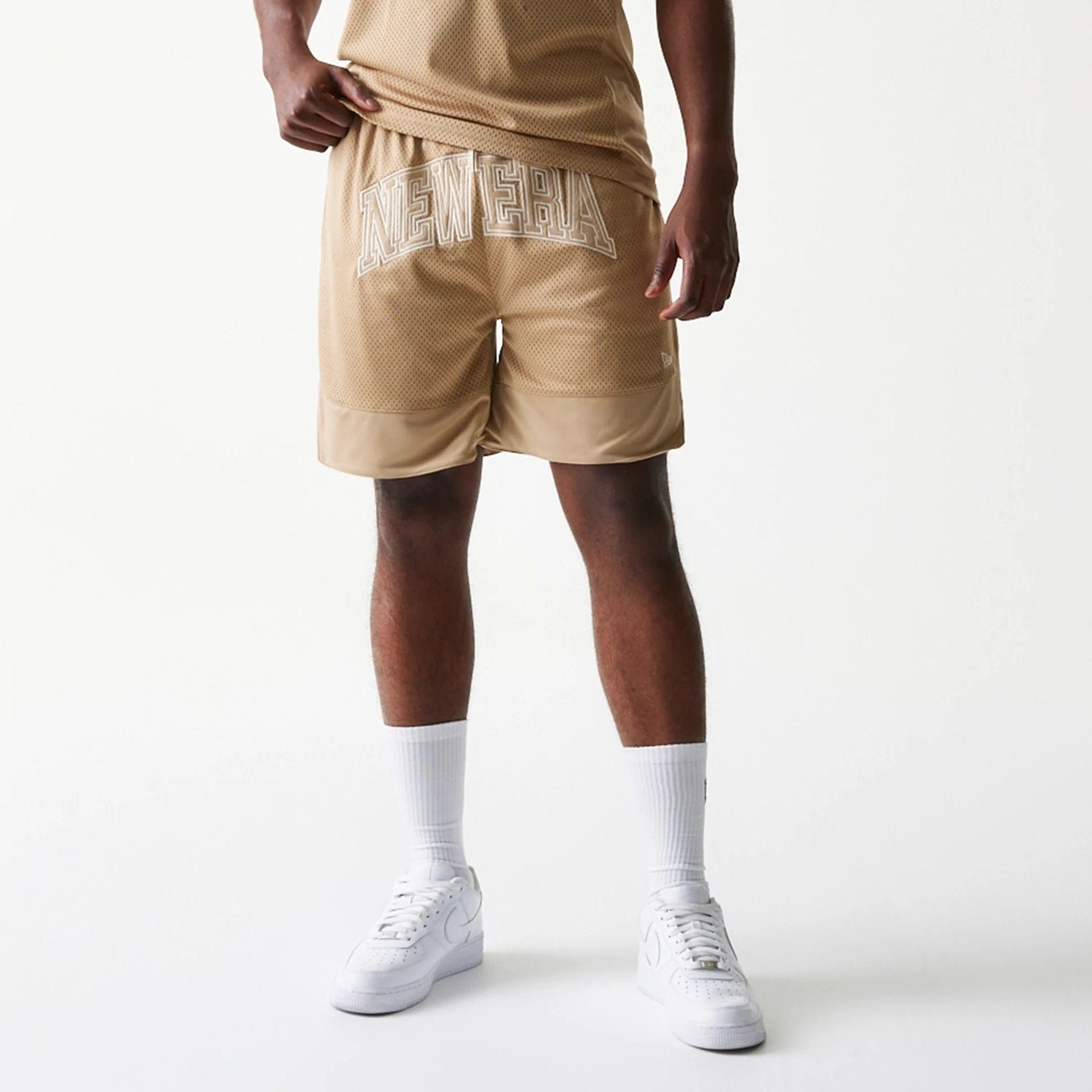The model is wearing this New Era Mesh Graphic Oversized Shorts in light beige. 3