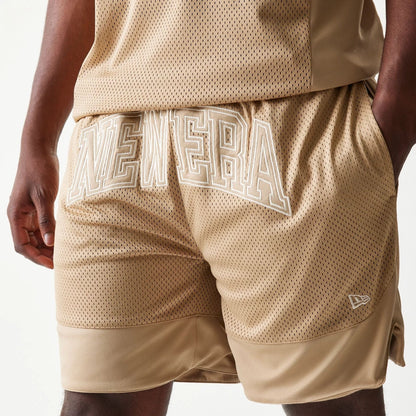 The model is wearing this New Era Mesh Graphic Oversized Shorts in light beige. 4