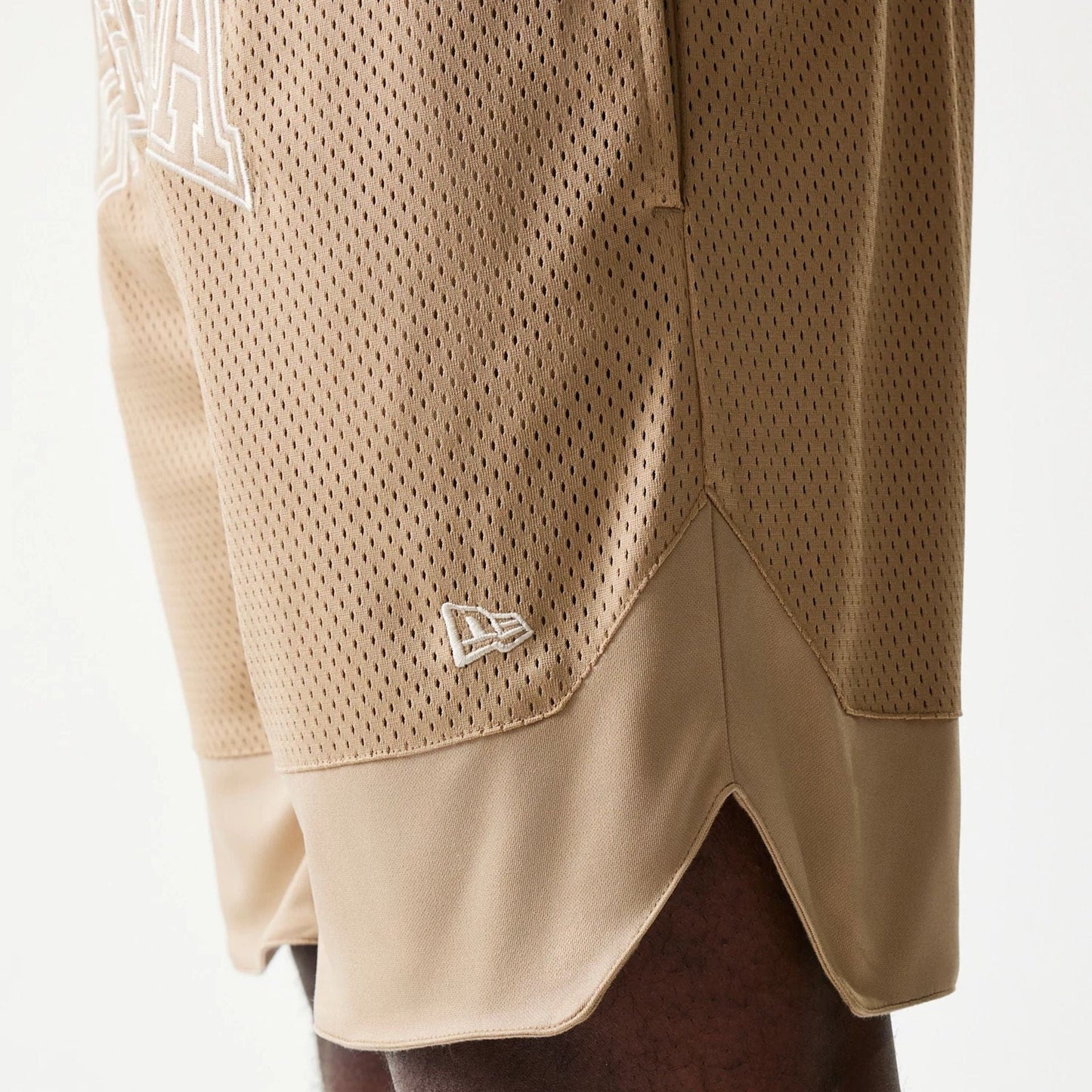 The model is wearing this New Era Mesh Graphic Oversized Shorts in light beige. 5